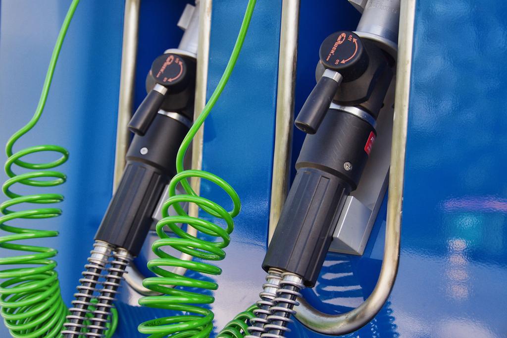 Na fotografiji je bližnji posnetek modre vodikove polnilne enote z napisom 'BLUE HYDROGEN – Clean energy solutions'. Na levi strani sta dve polnilni pištoli z zelenimi spiralnimi kabli, označeni z vrednostma 200 bar in 350 bar. Spodaj je nameščen rdeč varnostni gumb, desno pa digitalni upravljalni zaslon. Gre za del prve slovenske vodikove polnilnice na Petrolovem servisu v Lescah.